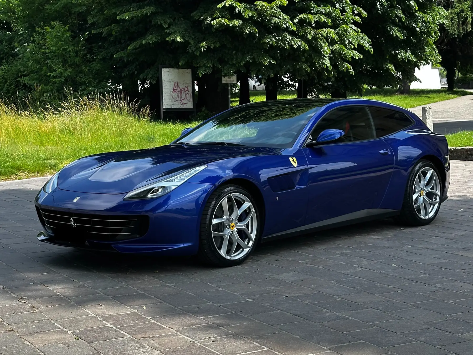 Ferrari GTC4Lusso blu di tre quarti sotto gli alberi