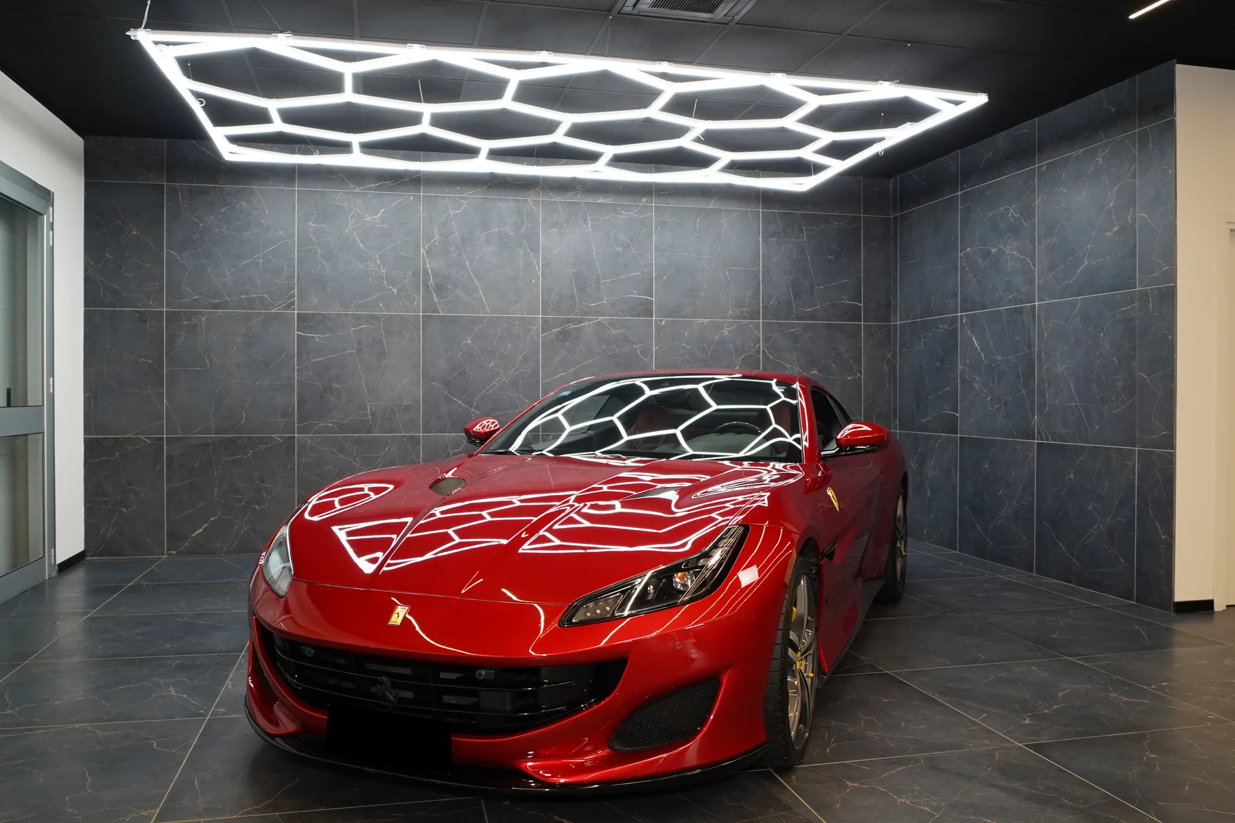 Ferrari Portofino rossa di tre quarti in un garage con luci a nido d’ape