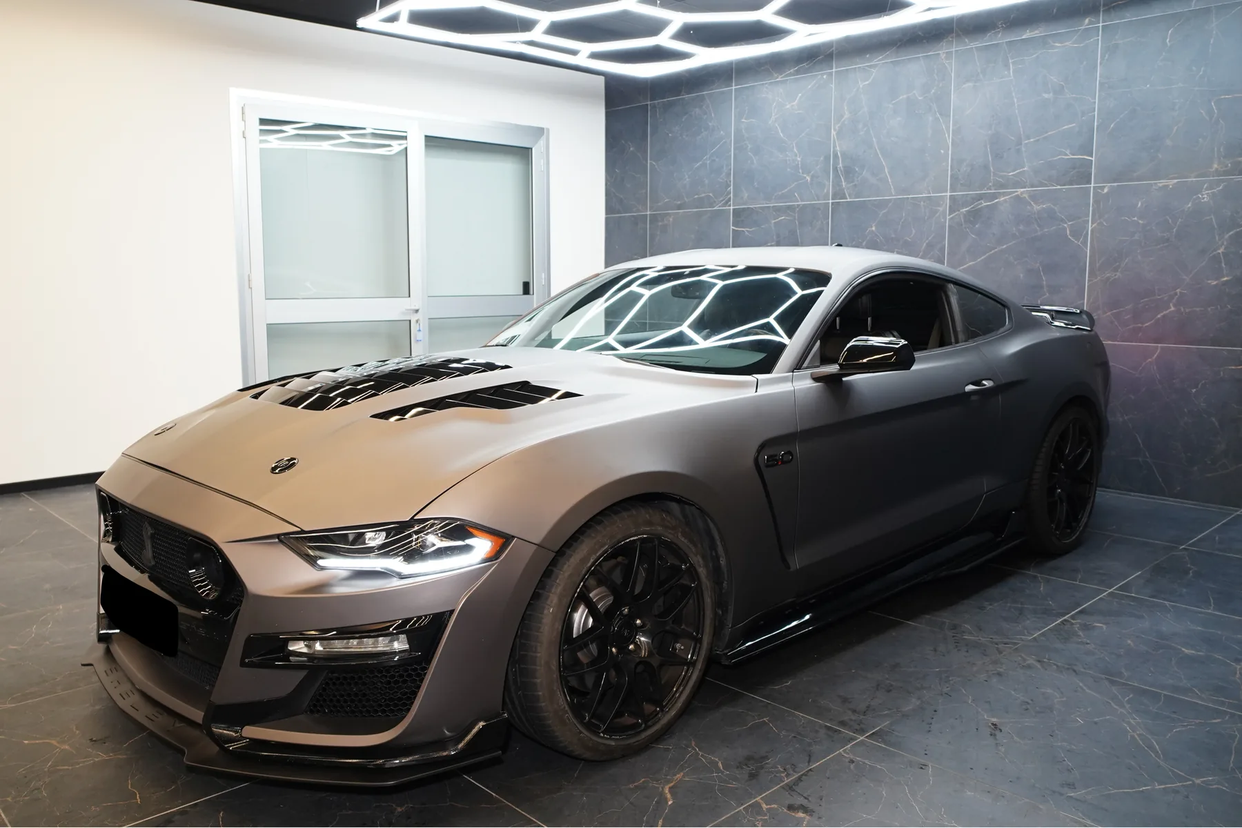 Coupé sportiva grigio opaco di tre quarti in garage