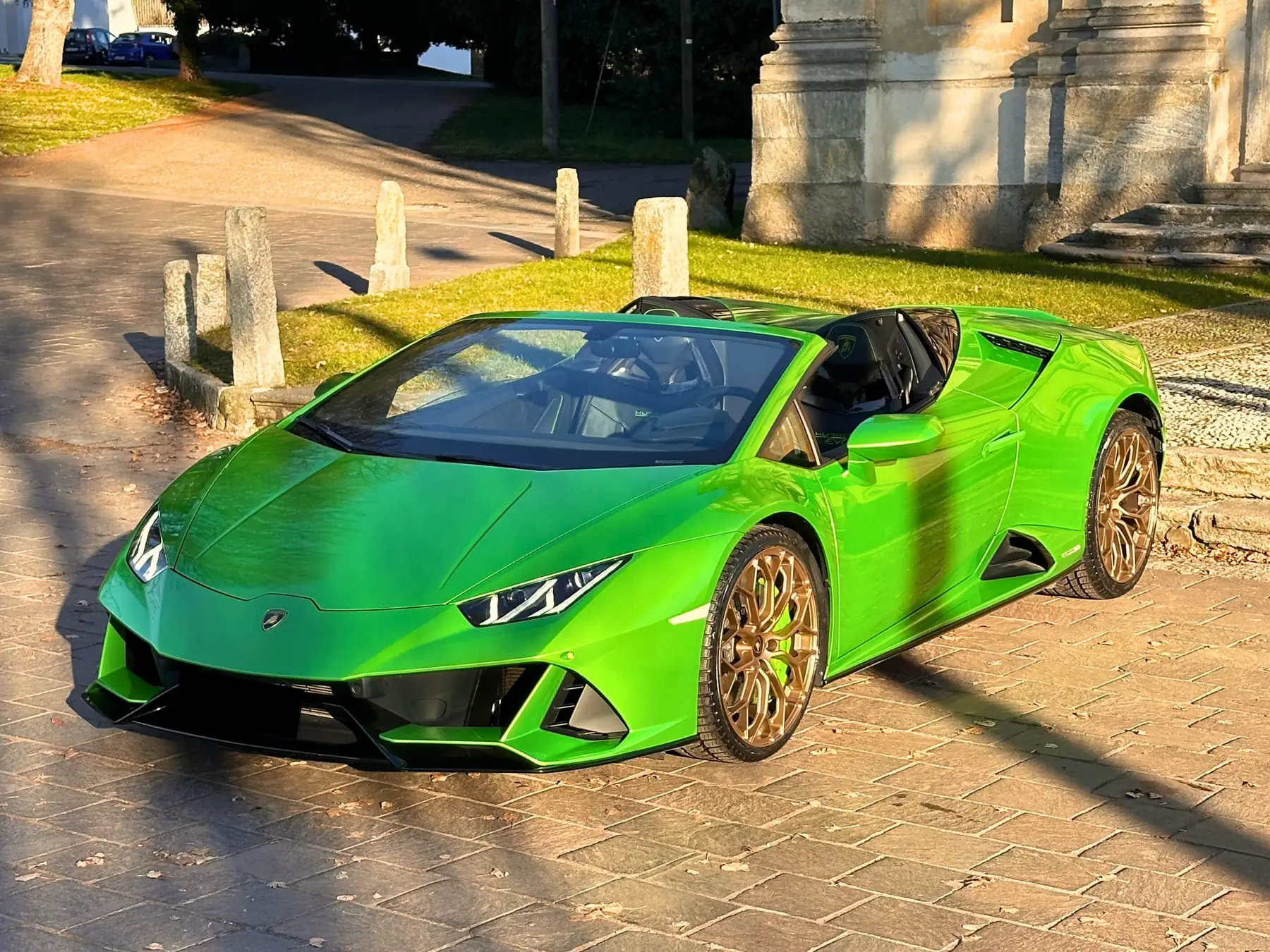 Lamborghini Huracán Evo Spyder verde con il tetto aperto, di tre quarti davanti a una chiesa