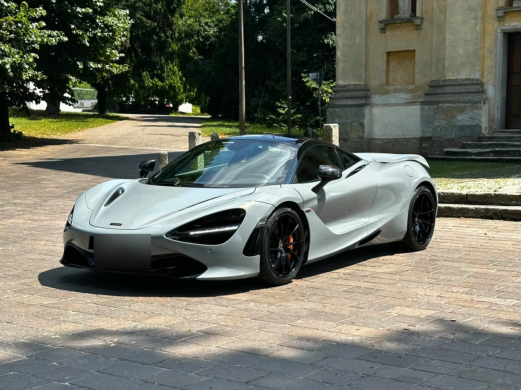 McLaren 720S grigio chiaro di tre quarti su un piazzale in pietra