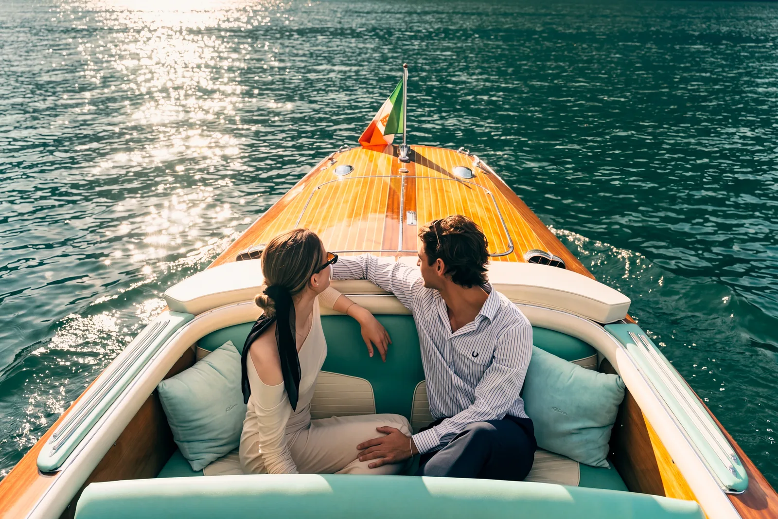 Una coppia seduta a bordo di un Riva, con l’acqua verde del lago intorno