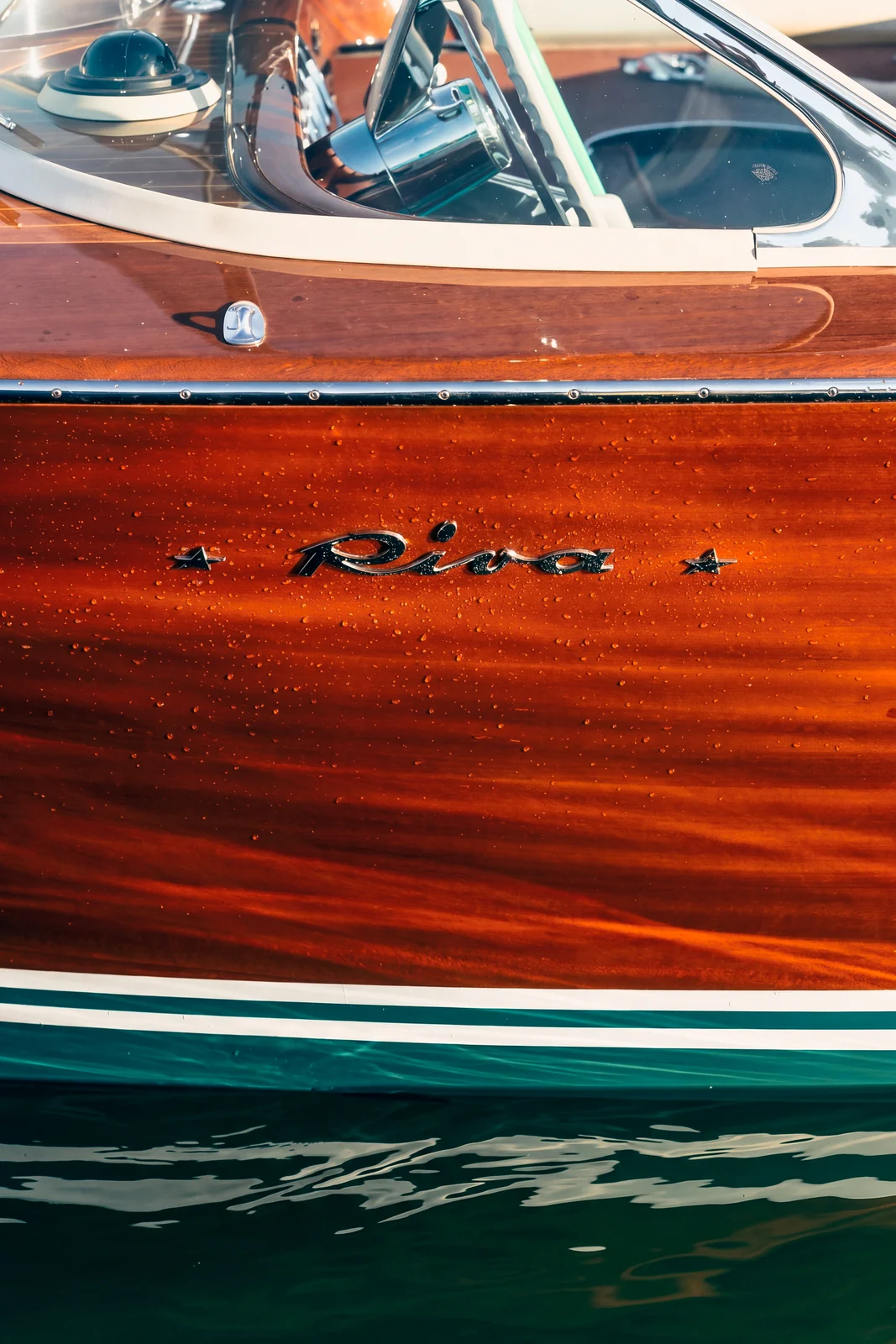 Le logo Riva gravé dans l’acajou verni de la coque, avec les reflets de l’eau